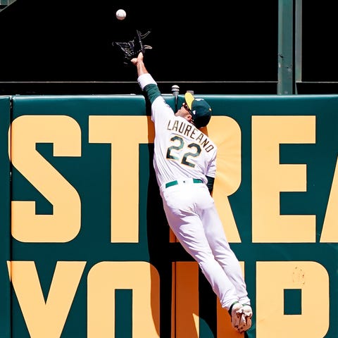 A's outfielder Ramon Laureano leaps at the wall...