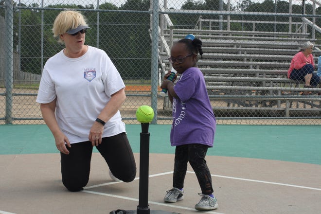 Miracle League volunteer Karen Agnello helps Abi Williams at the plate during a League game.