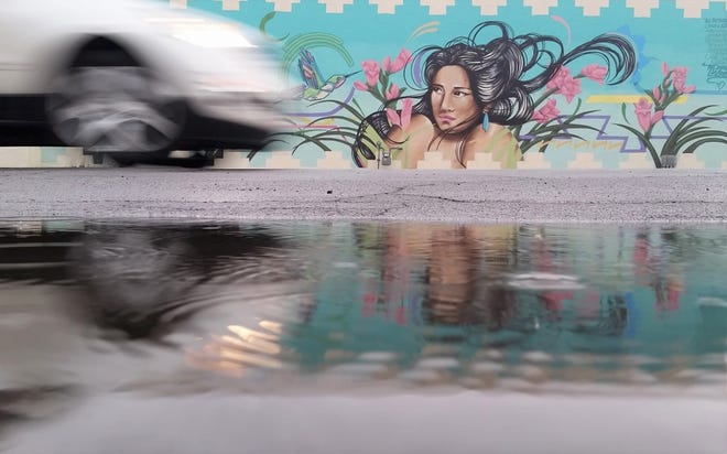 As light rain falls the afternoon of Monday, April 22, 2019, a vehicle passes by a puddle and a prominent mural on Las Cruces Avenue. A storm dropped about eight-hundredths of an inch of rain in downtown Las Cruces.