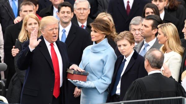Donald Trump takes the oath of office, while...