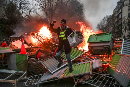 TOPSHOT - A yellow vest "Gilets Jaunes" anti-government protestor stands on a burning barricade in Paris on January 5, 2019 during clashes with security personnel. - France's "yellow vest" protestors were back on the streets again as a government spokesman denounced those still protesting as hard-liners who wanted only to bring down the government. Several hundred protestors gathered on the Champs Elysees in central Paris, where around 15 police wagons were also deployed, an AFP journalist said. Marches were underway in several other cities across France. (Photo by Zakaria ABDELKAFI / AFP)ZAKARIA ABDELKAFI/AFP/Getty Images ORIG FILE ID: AFP_1BZ86A