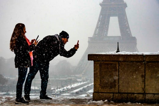 TOPSHOT - People take photos of a miniature Eiffel Tower with the Eiffel Tower in the background as snow falls over Paris on January 22, 2019. (Photo by Lionel BONAVENTURE / AFP)LIONEL BONAVENTURE/AFP/Getty Images ORIG FILE ID: AFP_1CI13E