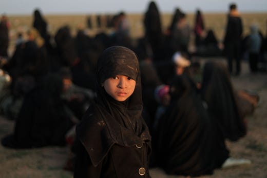 A child who fled the Islamic State (IS) group's last embattled holdout of Baghouz stands near families waiting to be searched by US-backed Syrian Democratic Forces (SDF) fighters (not pictured) in Syria's northern Deir Ezzor province, on Feb. 22, 2019. US-backed fighters trucked out civilians from the last speck of the Islamic State group's dying "caliphate" in Syria on Feb. 22, eager to press on with the battle to crush the jihadists. More than four years after IS overran large parts of Syria and neighbouring Iraq, and declared a "caliphate", they have lost all of it but a tiny patch in the village of Baghouz near the Iraqi border.