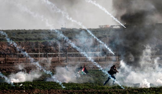 TOPSHOT - Palestinian protesters run from teargas fired by Israeli troops during a demonstration along the border with Israel, east of Gaza City on January 25, 2019. - A Palestinian was shot dead by Israeli fire during fresh clashes along the Gaza border today, the health ministry in the enclave said. (Photo by MAHMUD HAMS / AFP)MAHMUD HAMS/AFP/Getty Images ORIG FILE ID: AFP_1CQ3HC