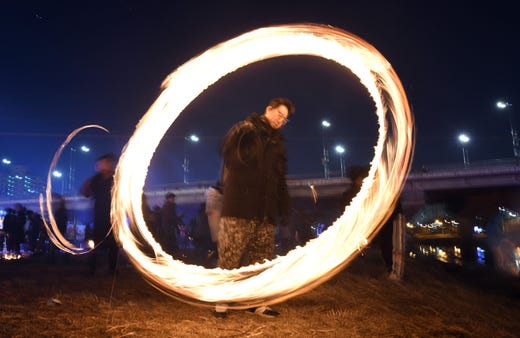 South Koreans spin cans of burning charcoal during an event to celebrate the upcoming first full moon of the lunar new year at a riverside park in Seoul on Feb. 17, 2019. South Koreans traditionally mark the occasion with a game involving cans filled with burning charcoal believed to fertilize the soil and rid it of unwanted pests, ensuring a prosperous harvest. 