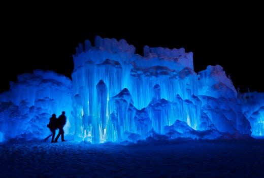 In this Saturday, Jan. 26, 2019 photo, a couple heads towards an entrance to a cavern at Ice Castles in North Woodstock, N.H. A team starts building massive walls in December to create a spectacular winter experience. (AP Photo/Robert F. Bukaty) ORG XMIT: NHRB201