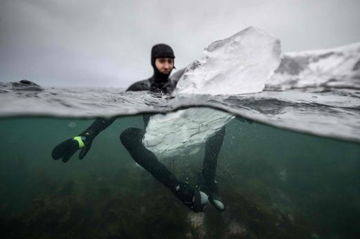 Swedish surfer Pontus Hallin waits for waves while sitting on his surfboard made of ice at the Delp surfing spot, near Straumnes, in the Lofoten Islands, over the Arctic Circle on Feb. 18, 2019.