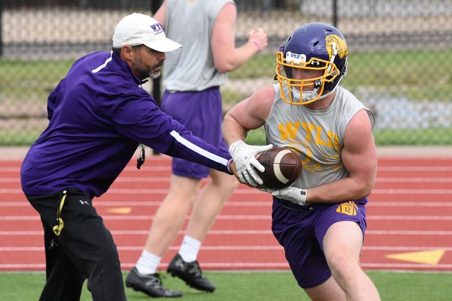 Wylie running back Jackson Smith takes a handoff from assistant coach Grant Martin during the first spring practice at Bulldog Stadium on Wednesday.