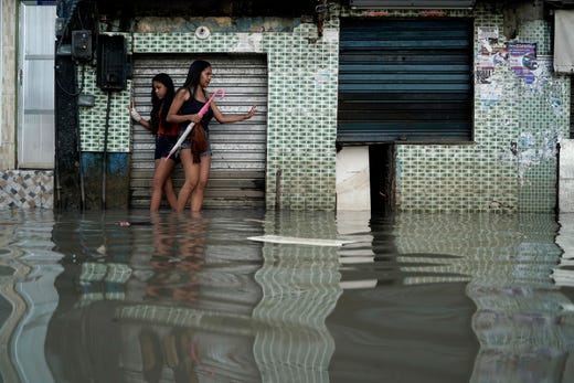 Women wade through a flooded street in Rio de Janeiro, Brazil, April 10, 2019. Heavy rains killed at least 10 people and left a trail of destruction in Rio de Janeiro raising questions about the city's preparedness to deal with recurring extreme weather. 