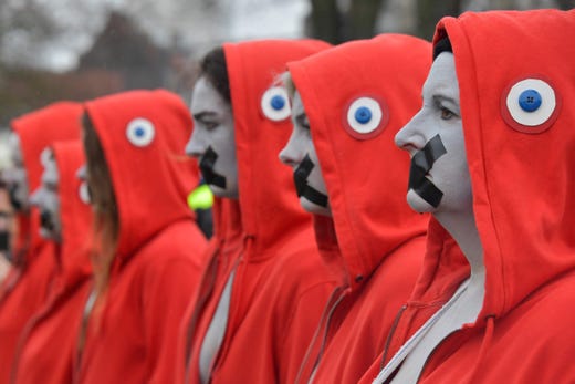 Protesters wearing a tricolor decoration on their hoods referring to the French Revolution, stand with their mouths taped during an anti-government demonstration called by the "Yellow Vest" movement in the French city of Lille, on March 2, 2019. 