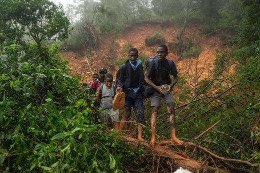 School students of St. Charles Luanga, rescued by members of the Zimbabwe Military, walk past a mudslide on March 17, 2019, covering a major road at Skyline junction in Chimanimani, Zimbabwe, after tropical cyclone Idai barrelled across the southern African nations with flash floods and ferocious winds. 