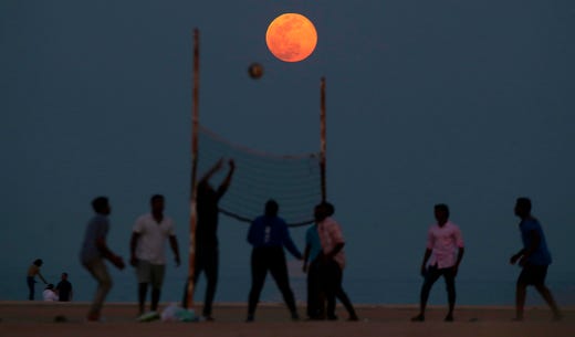 People play volleyball on the beach as the Pink Moon rises in the sky over the Salmiya district in Kuwait some 12 miles east of the capital Kuwait City on April 19, 2019. 