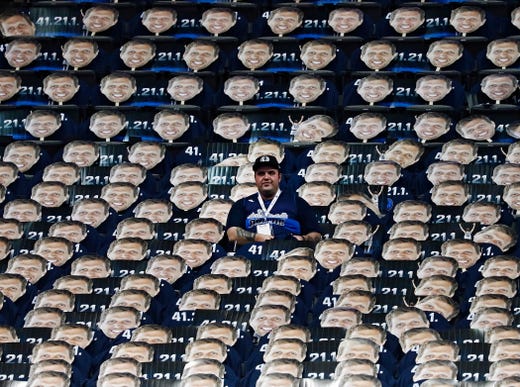 A fan sits in the stands surrounded by large cut outs of the face of Dallas Mavericks player Dirk Nowitzki before his final game in the NBA against the Phoenix Suns at the American Airlines Center in Dallas on April 9, 2019.