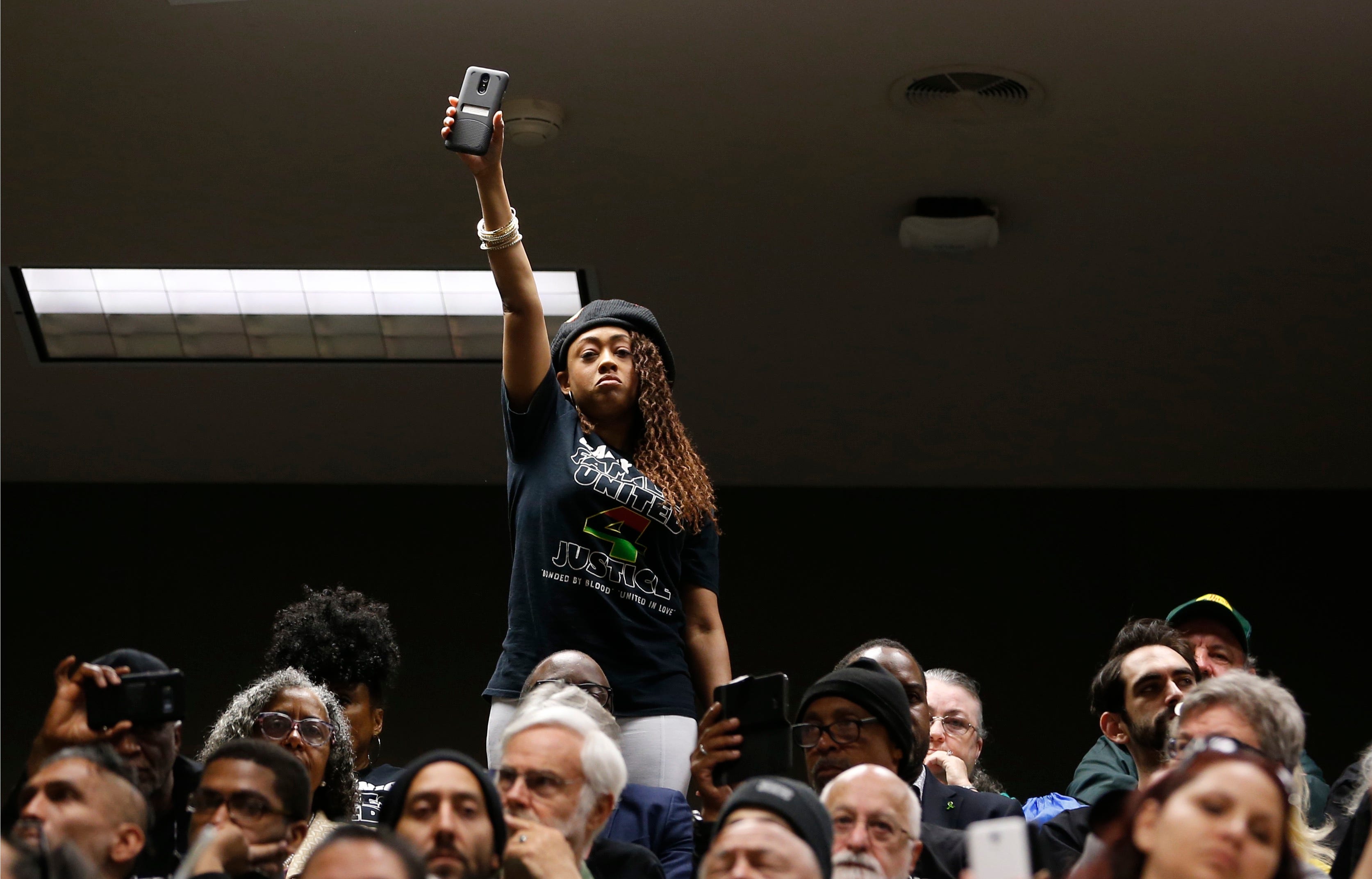 Jamilia Land, a friend of the family of police shooting victim Stephon Clark, holds up a cell phone during a hearing on legislation to restrict the use of deadly force by police, Tuesday, April 9, 2019, in Sacramento, Calif. Sacramento Police officers mistook the cell phone Clark was holding for a gun when he was shot and killed in 2018.