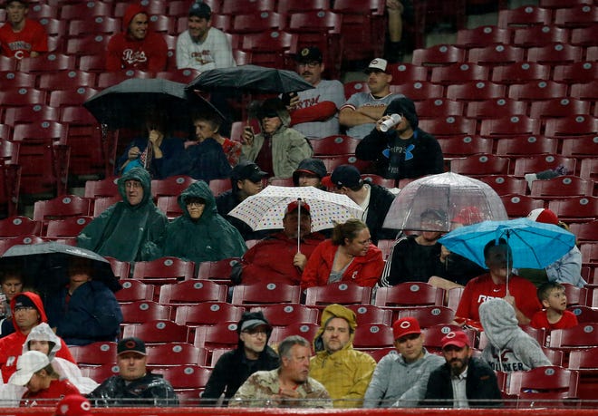 Fans pop umbrellas as rain falls in the seventh inning of the MLB National League game between the Cincinnati Reds and the Atlanta Braves at Great American Ball Park in downtown Cincinnati on Thursday, April 25, 2019.