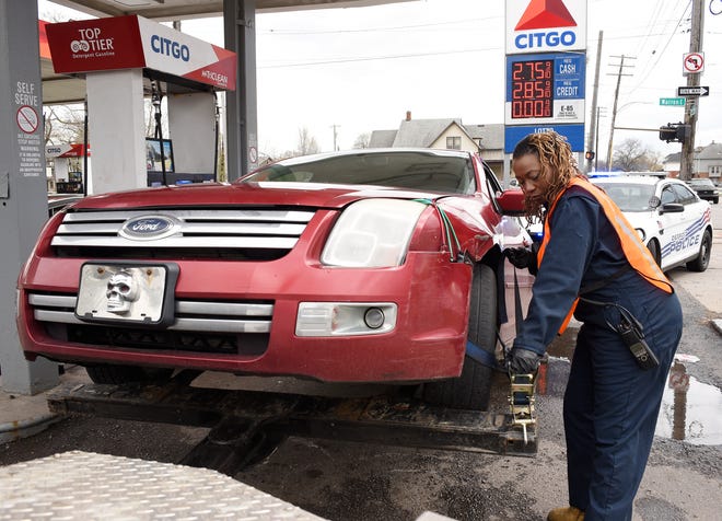 Erin Reed, a city of Detroit employee,  prepares a car for towing at a gas station on Van Dyke in Detroit on April 26. Detroit police officials credit a sharp decline in auto thefts to the city banning a company from the towing rotation and assuming most towing duties.