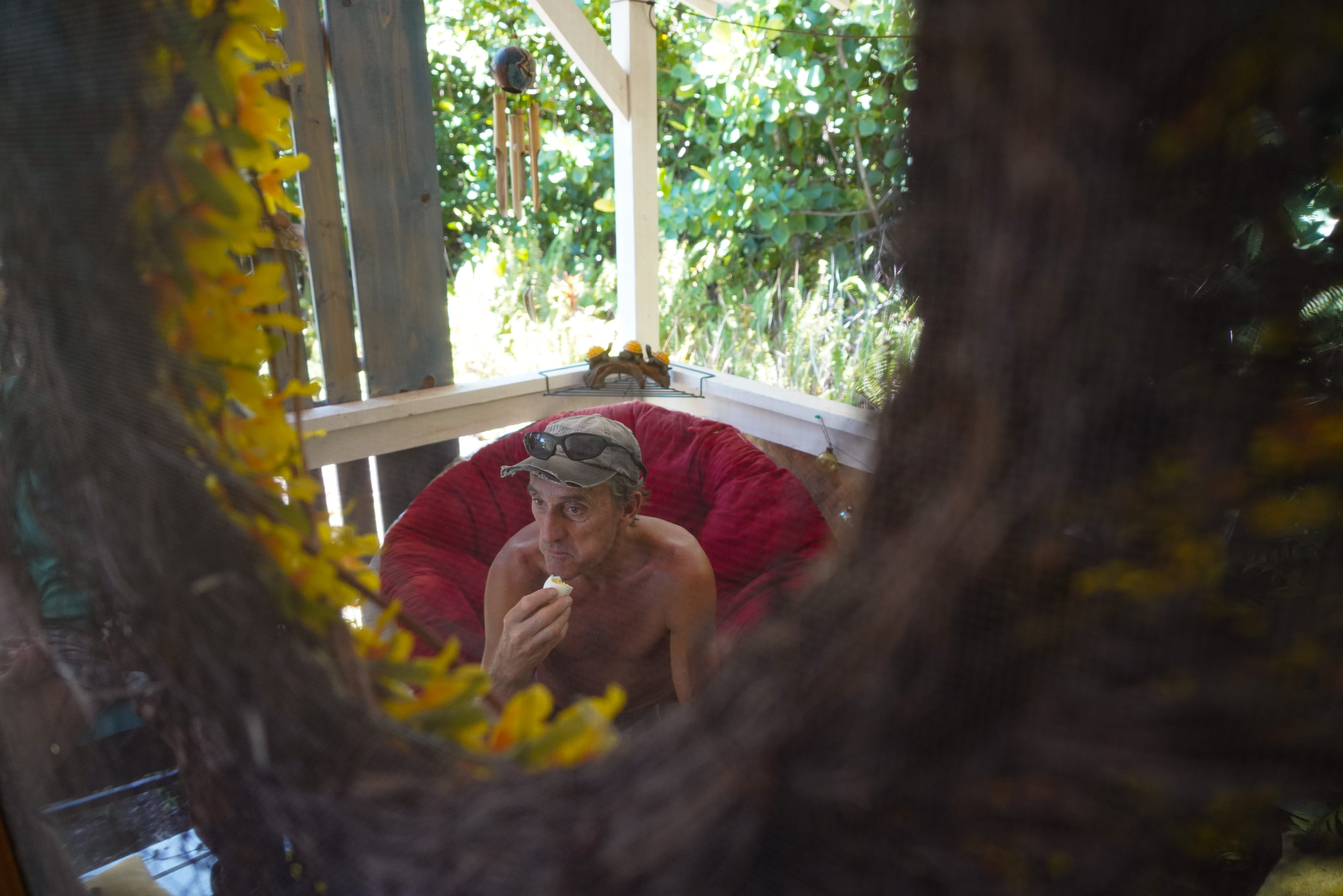 Stan Smith eats a hardboiled egg while taking a break from inspecting and cleaning his property on Hawaii's Big Island. The Smith's fruit farm was partially destroyed by the 2018 lava flow, and the couple have bought a neighbor's house with the intent to rebuild their farm.