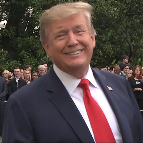 President Trump smiles at reporters outside the...