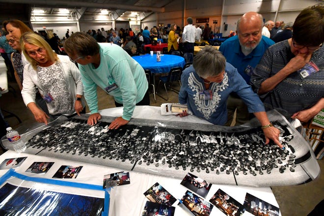 Attendees look over a class portrait of the Cooper High School Class of 1969 during Friday's reunion of Cooper and Abilene high schools from that year at the Taylor County Expo Center.