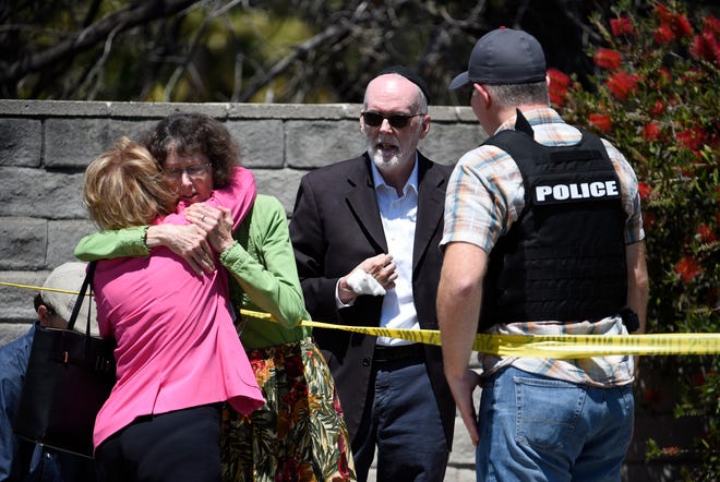 Two people hug as another talks to a San Diego County Sheriff's deputy outside of the Chabad of Poway synagogue, Saturday, April 27, 2019, in Poway, Calif.