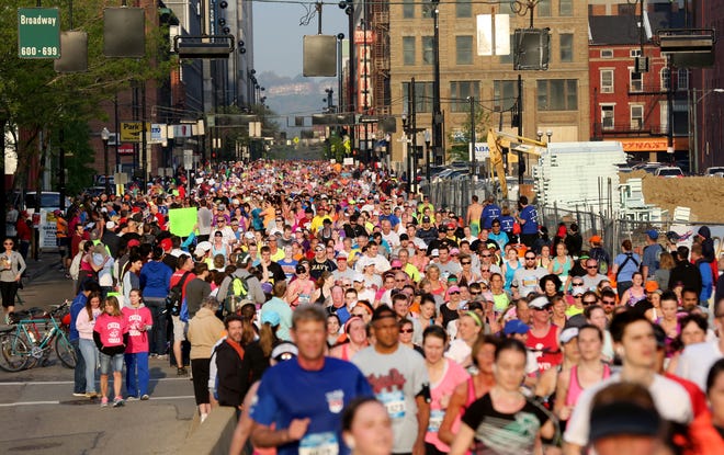 Runners and walkers in the 17th Flying Pig Marathon make their way along Seventh Street past the 5-mile marker of the downtown Cincinnati race on Sunday, May 3, 2015.