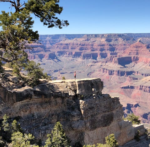 A visitor poses for a photo on a ledge off the Gra