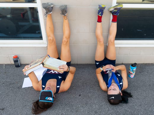 West runners Janie Holecek studies for her AP European history class as she and teammate Hannah Burkhart rest their legs after helping win the 4x800 meter relay at the KIL Championships at Hardin Valley Academy on Tuesday, April 30, 2019. 