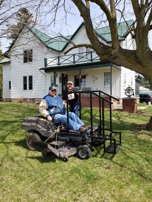 Bob on his mower with his engineer son, Russ, checking to see if his creation is working properly.