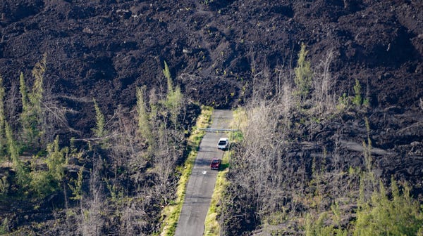 Cars parked at the end of a lava flow hint at the...