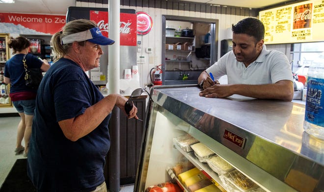 Deepan Patel, general manager of the recently remodeled Zion Country Store, takes a customer's order at the deli counter on Wednesday, The Zion Country Store got new management on April 19. Patel said along with the new look, there is also larger sandwiches and more variety.