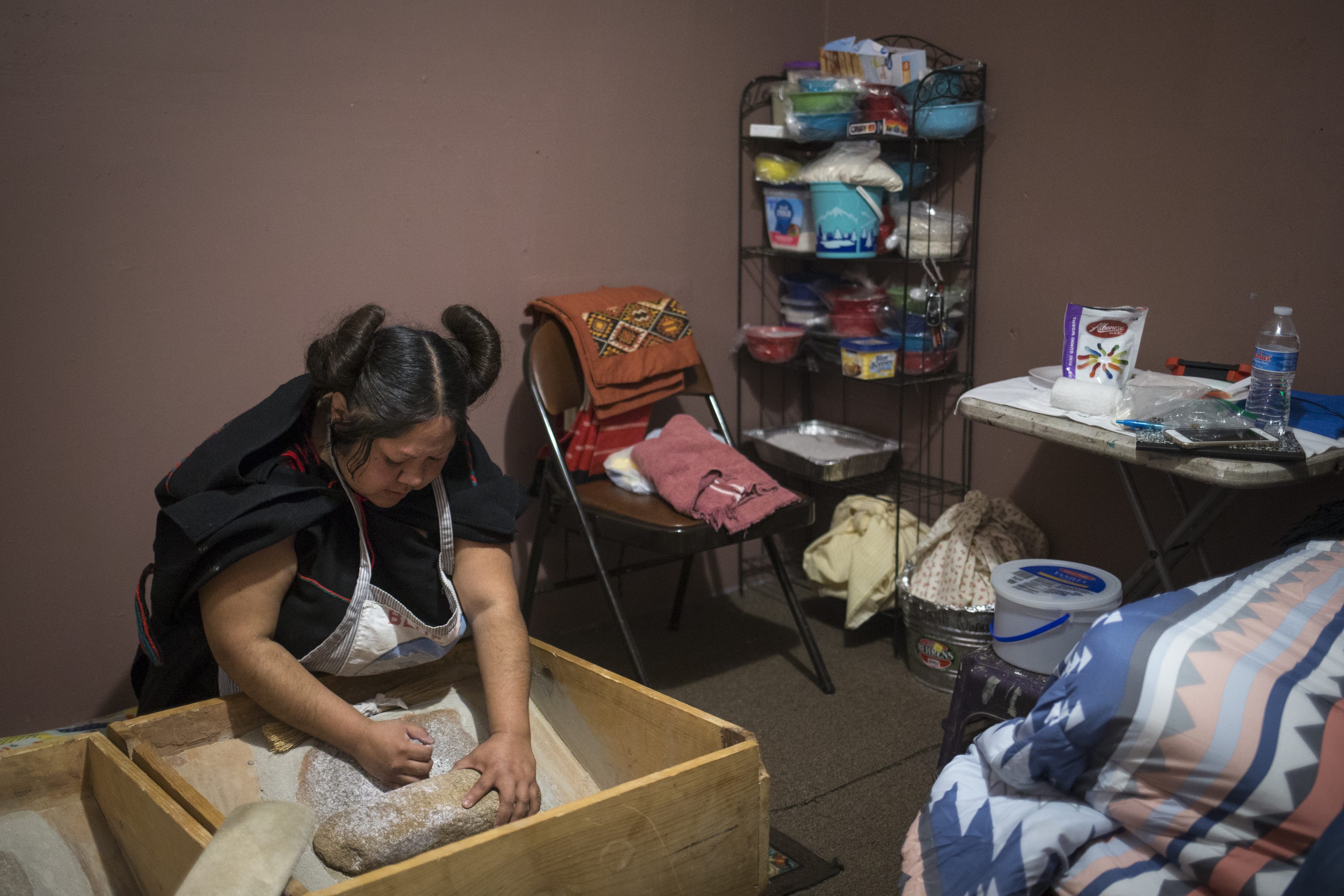 Kara Honanie grinds corn on March 22, 2019, in Moenkopi, Arizona. She was responsible for preparing meals for the groom's family and relatives while she stayed at her in-laws' house.