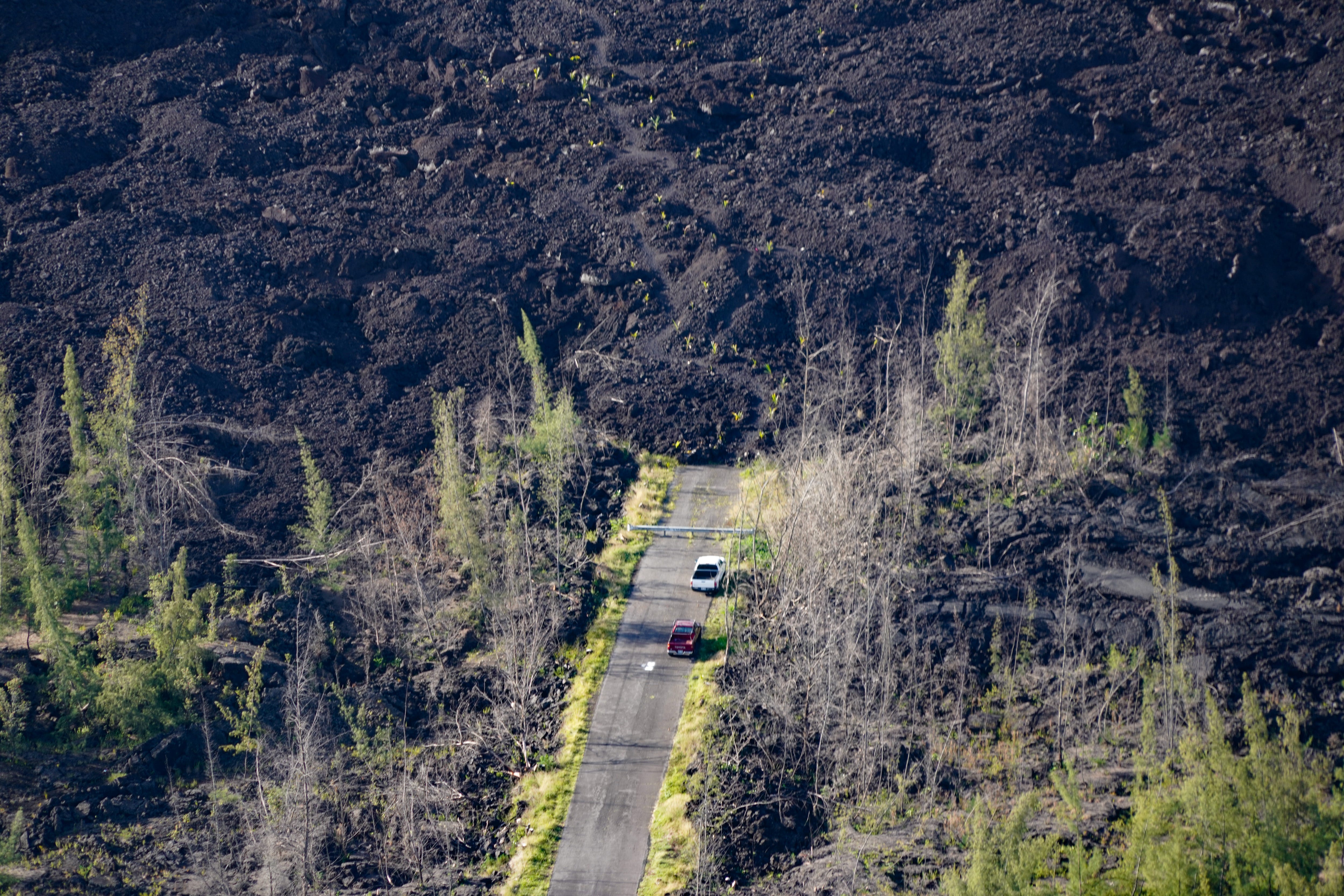 Cars parked at the end of a lava flow hint at the journey some Big Island residents have been taking to reach their properties, which have been cut off from the roads for nearly a year.
