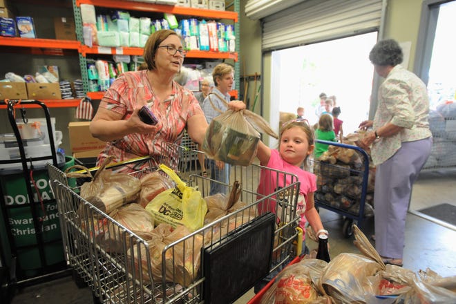 Black Mountain Primary student Karter McIntosh delivers a bag of food to the food pantry at Swannanoa Valley Christian Ministry, as executive director Cheryl Wilson looks on.