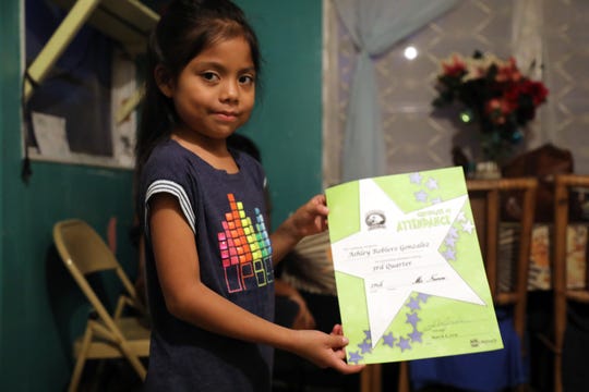 Ashely Gonzalez shows an attendance award she earned in school in Immokalee. Although she and her siblings live in crowded trailer conditions with no private space to study, she's doing well in school.