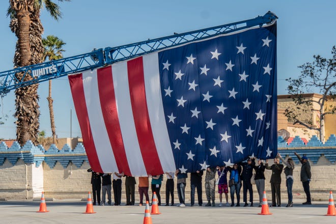 Volunteers came forward to hold the 30 by 36-foot American flag off the ground as Whites Steel’s crane was raising it.
