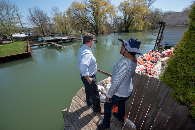 U.S. Sen. Gary Peters, left, is given a tour May 5 of flood-damaged areas around the canal that separates Harbor Island and Klenk Island by Judge Deborah Thomas who lives on the canal, in Detroit. The persistent issues are prompting officials to require sandbags at city sites.