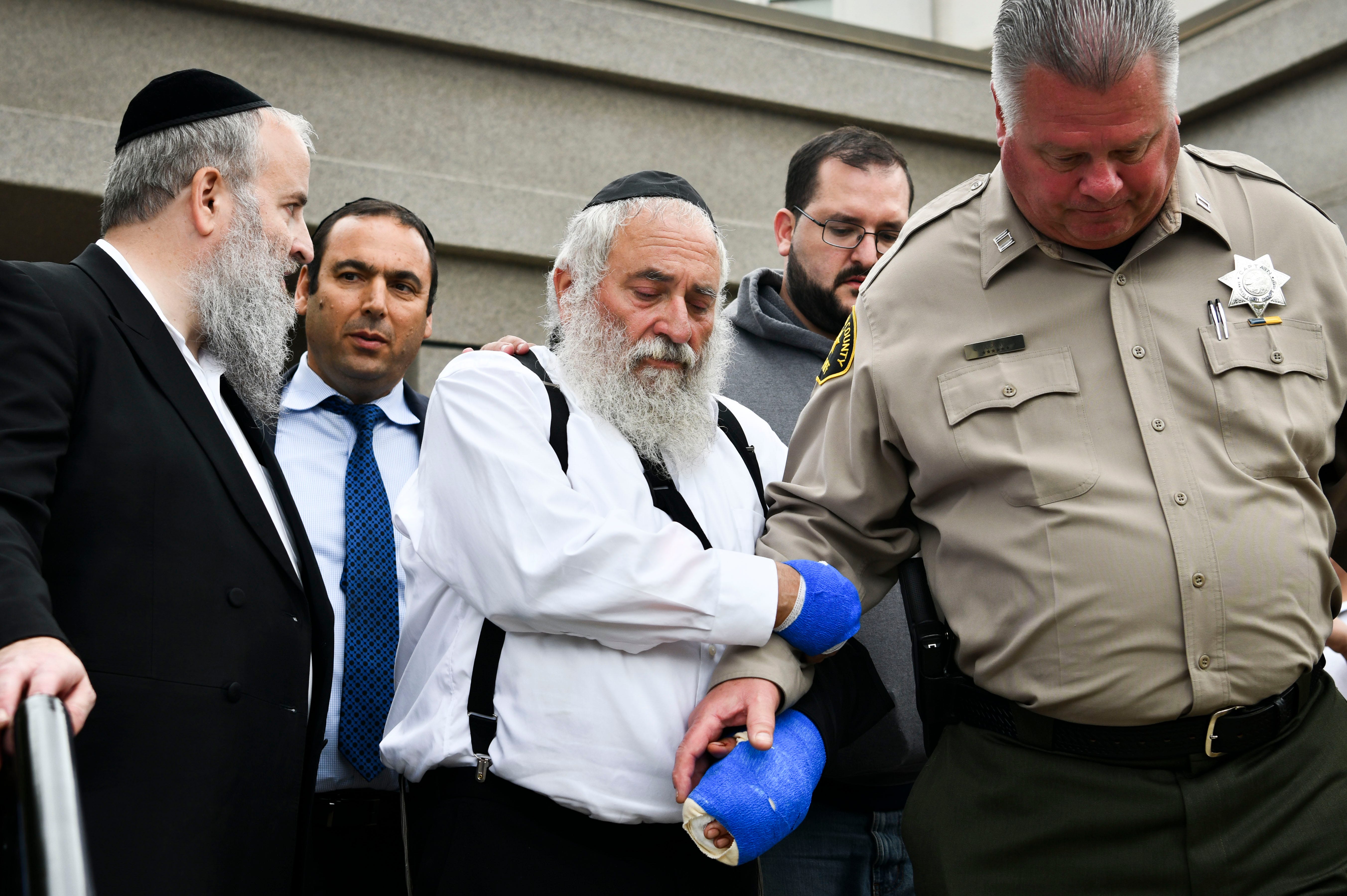 Rabbi Yisroel Goldstein is escorted out of of Chabad of Poway synagogue after speaking to the media on April 28, 2019.