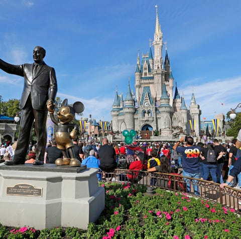 Guests watch a show near a statue of Walt Disney...