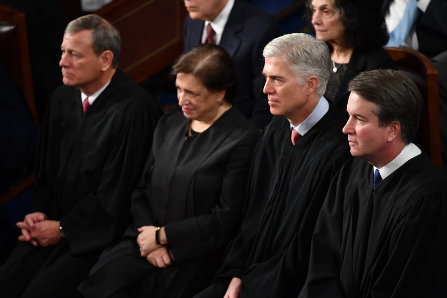 New Supreme Court Associate Justice Brett Kavanaugh, right, listens to President Trump's State of the Union address in February along with Chief Justice John Roberts, left, and Associate Justices Elena Kagan and Neil Gorsuch.