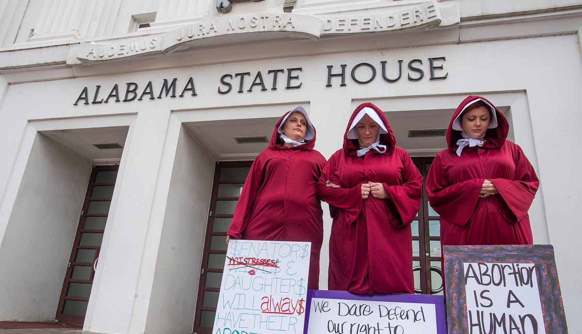 Women dressed as handmaids protest against a near-total abortion ban outside the Alabama State House in Montgomery, Ala., on April 17, 2019.