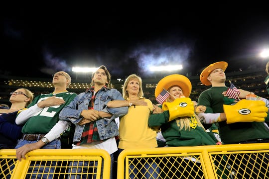 Green Bay Packers fans lock arms during the national anthem before the game against the Chicago Bears on Thursday, Sept. 28, 2017, at Lambeau Field in Green Bay, Wis. To demonstrate unity, Green Bay Packers quarterback Aaron Rodgers requested that fans join players, locking arms in the stands during the anthem.