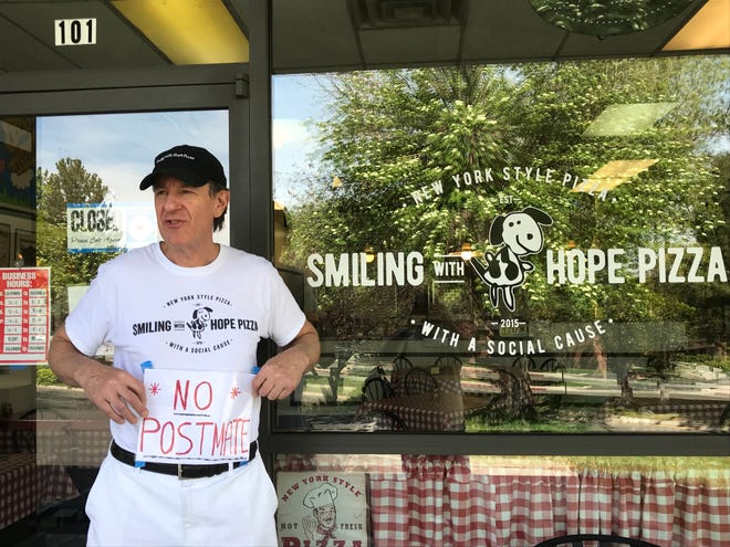 Walter Gloshinski, co-owner of nationally recognized Smiling with Hope Pizza of Reno, holds the "No Postmate" sign usually displayed in the restaurant's window. He didn't want to participate with the Postmates delivery service; it took dozens of requests to have the pizzeria removed from the app.
