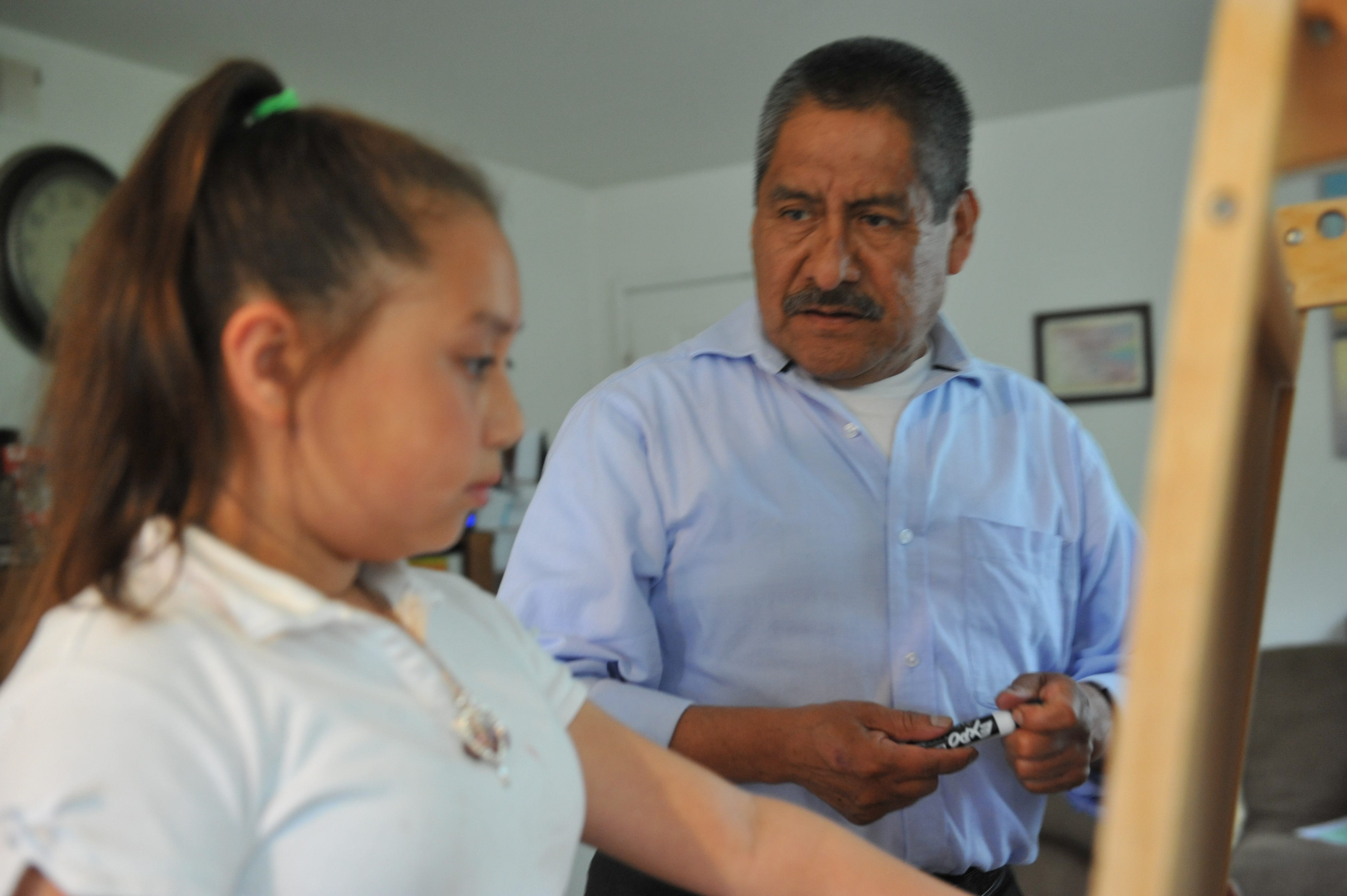 Adolfo González helps his granddaughter Kayla with her homework using the whiteboard in his Salinas home.