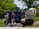 Officers prepare an armoured personnel carrier near the landing site for the Tennessee Highway Patrol helicopters across the street from Midway High School Friday afternoon. Officers continued to search the woods of South Roane County Friday looking for Leon Houston after he and his brother, Rocky, allegedly ambushed and killed Deputy Bill Jones, 53, and friend Mike Brown on the evening of Thursday, May 11.