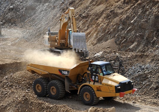 A mineral ore truck is loaded with material in an open pit mine.