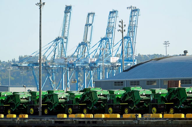 In this May 10, 2019, file photo John Deere Agricultural machinery made by Deere & Company sits staged for transport near cranes at the Port of Tacoma in Tacoma, Wash.