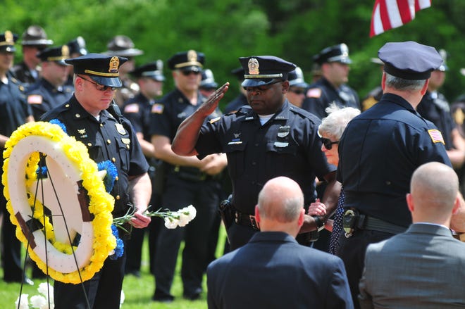 Officer Aaron Stevens salutes after a flower was placed in memory of an officer during a Peace Officers Memorial Service at Wayne County Veterans Park.