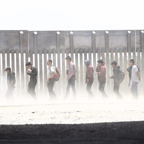 Migrants walk while being detained by Border...