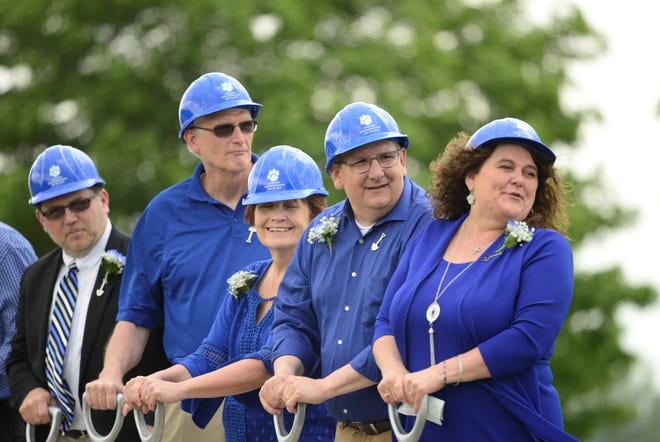 Wynford school board member Rhonda Rowland, right, and other officials stand on a flat-bed trailer hauled by a tractor at a ceremonial groundbreaking for the district's new junior high/high school.