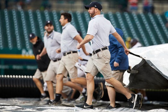 Grounds crew pull the tarp onto the field during the seventh inning at Comerica Park on Sunday.